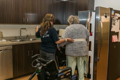 Staff assisting a resident in a kitchen area