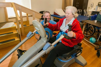 Resident using exercise equipment with staff assistance
