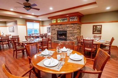Dining room with tables set for meals and a fireplace