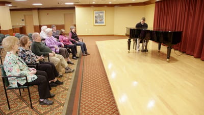 Residents enjoying a piano performance in a common area