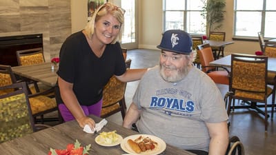 Staff member with resident enjoying a meal at the dining area