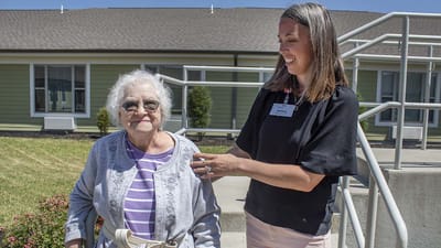 Staff assisting a resident outside on a sunny day