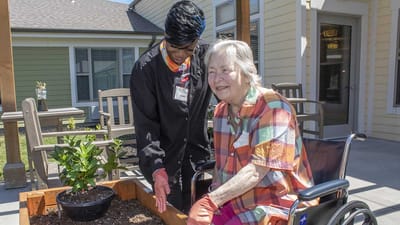A caregiver interacting with a resident in a garden area