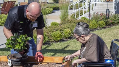 Resident and staff gardening together in an outdoor space
