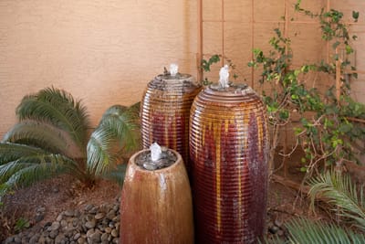 Three decorative water fountains surrounded by greenery