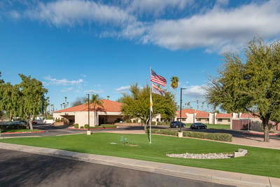 Exterior view of Mi Casa Nursing Center with landscaping and flag