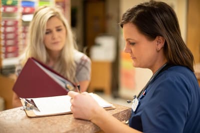 Staff member assisting a resident at the reception desk