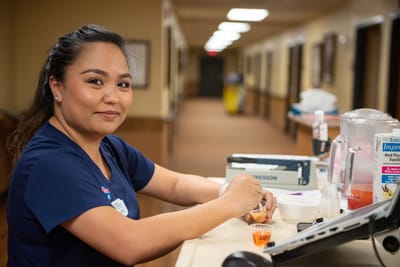 Staff member preparing medication in a facility hallway