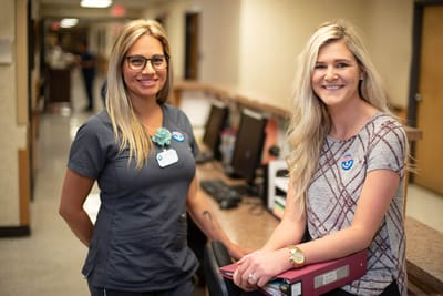 Two smiling staff members in a corridor