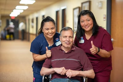 Staff and resident giving thumbs up in a hallway