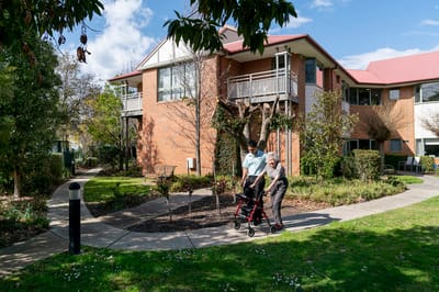 A resident and staff member walking outside the facility