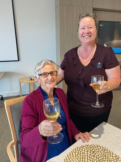 Resident and staff member toasting with drinks