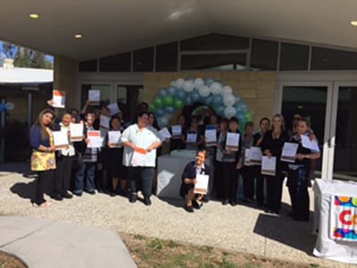 Staff and residents celebrating outside with certificates