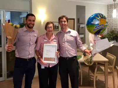 Staff celebrating a resident's retirement with flowers and balloons