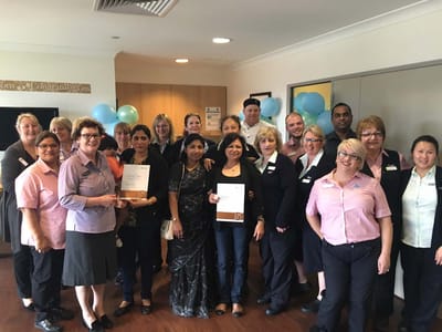 Staff and residents celebrating with certificates in a common area