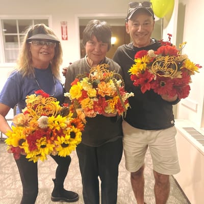Residents and staff holding flower arrangements in a common area