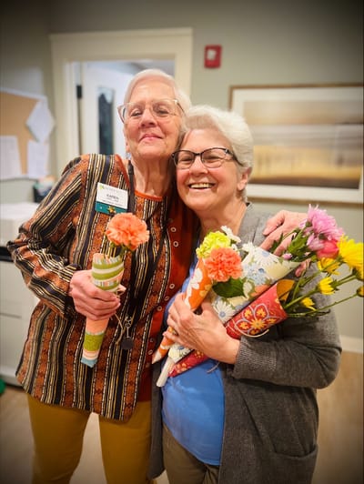 Two smiling residents holding flowers in a common area