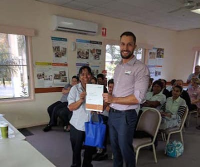 Staff presenting an award in a common area with residents