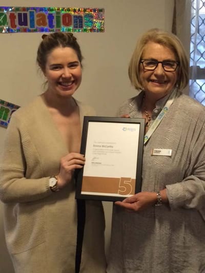Two women celebrating a milestone achievement with a certificate