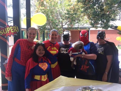 Staff and residents in superhero costumes at an event