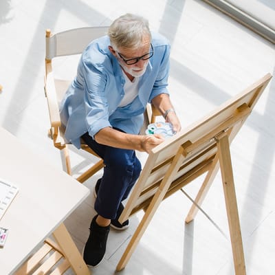 Senior man painting in a well-lit activity room