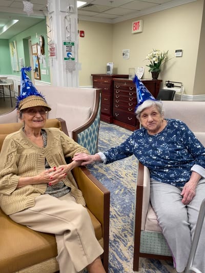 Two residents celebrating with party hats in a lounge area