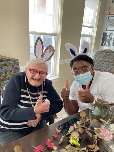Two residents with bunny ears giving thumbs up in an activity room