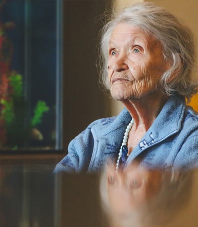 An elderly woman thoughtfully gazing indoors