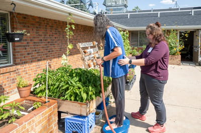 Resident and staff member gardening together