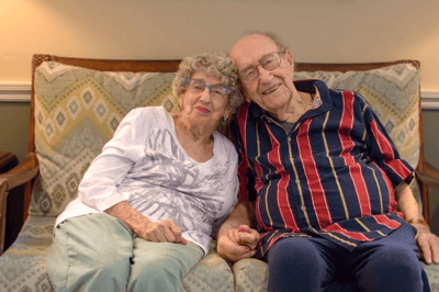 Two joyful residents sitting together on a couch.