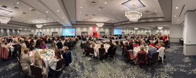 Large dining event with people seated at tables.