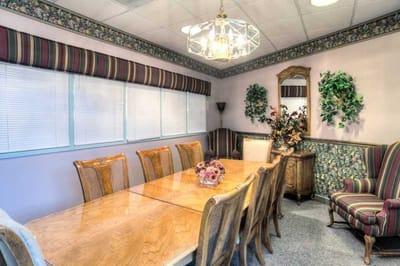 Dining area with large wooden table and floral decor.
