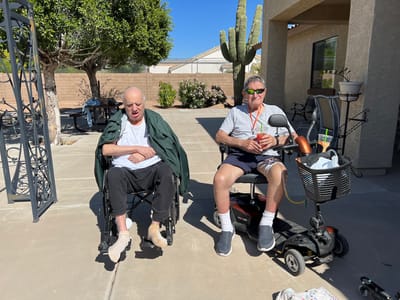 Two residents relaxing outdoors in wheelchairs.
