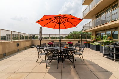 Outdoor terrace with seating and orange umbrella.
