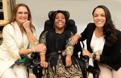 Three women smiling together in a caring environment.