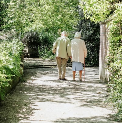Elderly couple walking hand-in-hand on a path