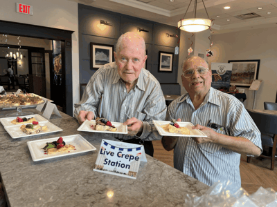 Two residents enjoying crepes at a dining event.