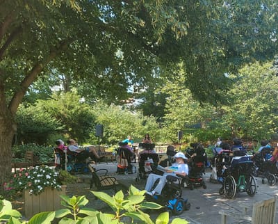 Residents enjoying a garden space in wheelchairs.