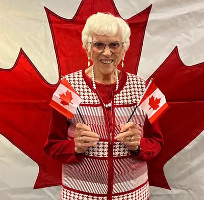 Senior woman celebrating with Canadian flags.