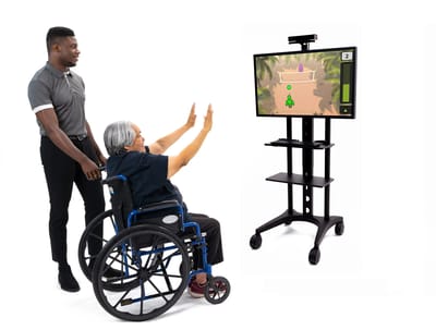 Older adult engaging with staff through a gaming system.
