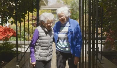 Two elderly women enjoying a garden pathway.