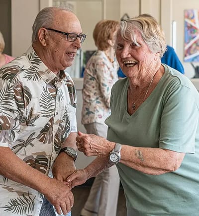 Two seniors enjoying a dance in a common area.