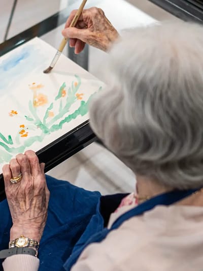 Elderly woman participating in a painting activity.