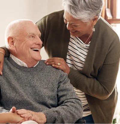 Smiling elderly man with caregiver in a cozy space.