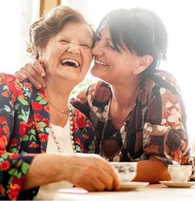 Two women sharing a joyful moment indoors.