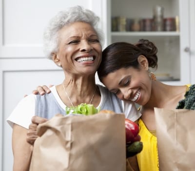 Two women smiling with grocery bags