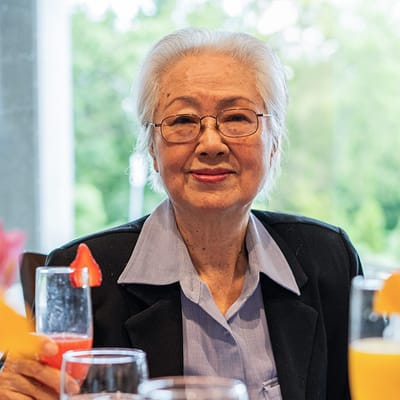Senior resident enjoying a drink at a dining table.