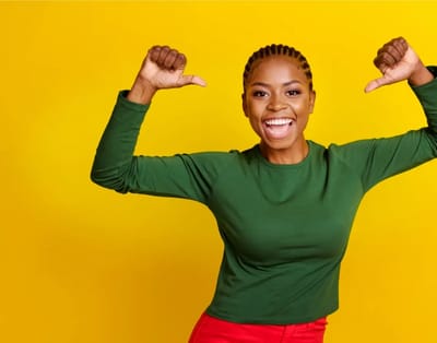 Smiling woman with braids against a yellow background.