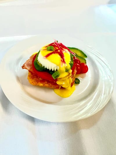 Plate of eggs benedict garnished with vegetables
