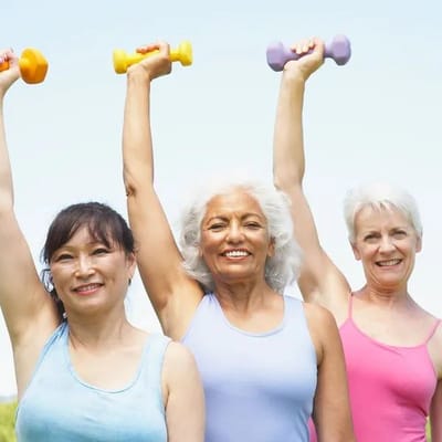 Three women exercising with dumbbells outdoors